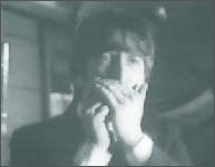 John Lennon in A Hard Day's Night: John plays the harmonica in the train baggage car during the filming of I Should Have Known Better.
