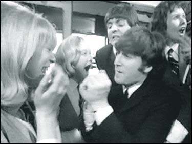John Lennon in A Hard Day's Night: John craziness delights Patti Boyd and other fans in a fun scene from the boys' first feature film, A Hard Day's Night.